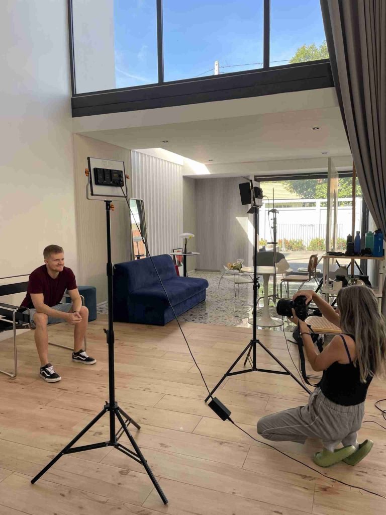 Behind the scenes image of Simon from Sculpt Websites having his professional photos taken in a studio with tripods and props all around.